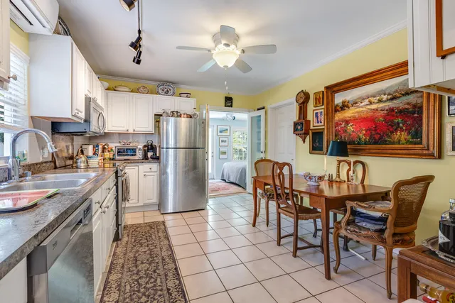 a kitchen with stainless steel appliances granite countertop a dining table chairs refrigerator and cabinets