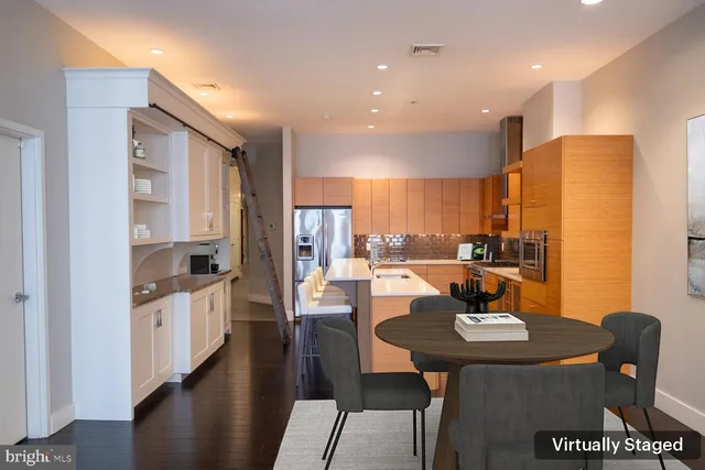 a kitchen with stainless steel appliances granite countertop a refrigerator a stove a sink a dining table and chairs with wooden floor