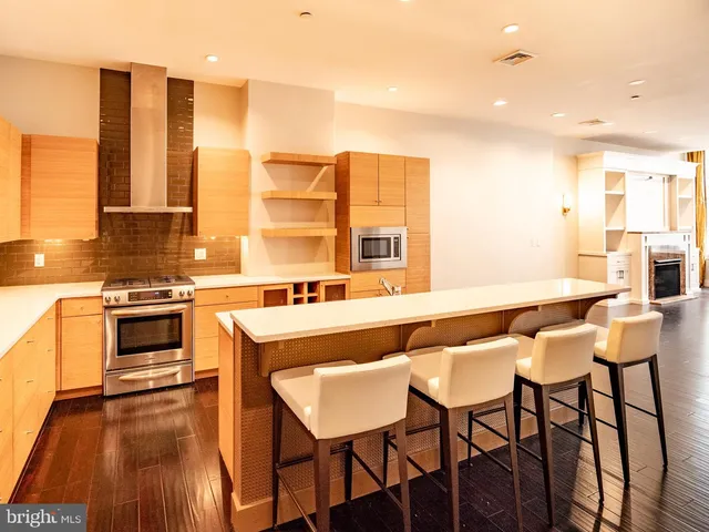 a living room with stainless steel appliances kitchen island granite countertop furniture and a wooden floor
