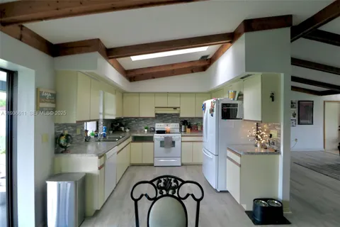 a kitchen with sink a refrigerator and chairs