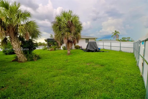 a view of a house with a yard and palm trees