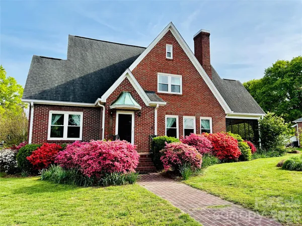 a front view of a house with a big yard and potted plants