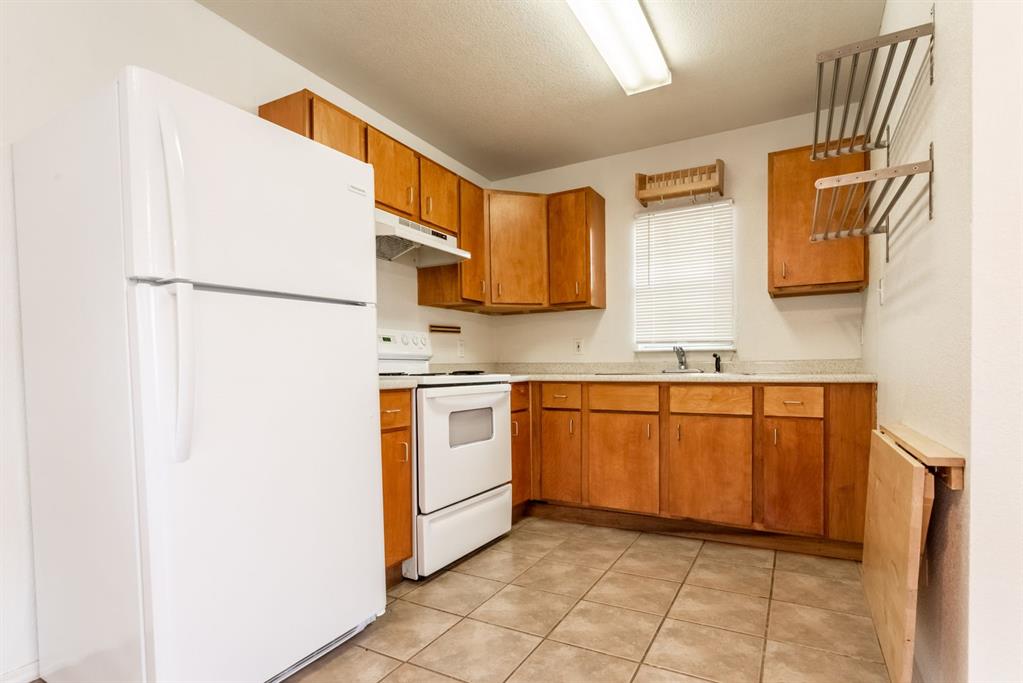 4704 Evans Avenue, Unit B Austin, TX 78751 - Photo 4 of 8 Kitchen with white appliances, light countertops, brown cabinets, under cabinet range hood, and light tile patterned floors