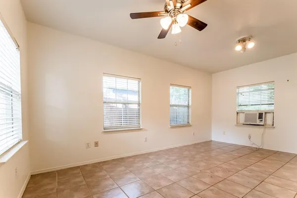 a view of an empty room with a window and a chandelier fan