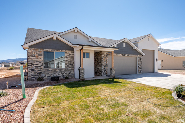 4978 North 75 East Enoch, UT 84721 - Photo 42 of 60 Craftsman house featuring stone siding, an attached garage, a front lawn, driveway, and roof with shingles