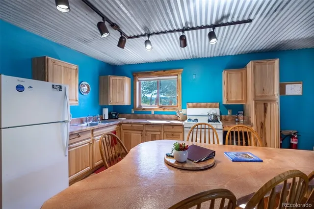 a kitchen with stainless steel appliances granite countertop a refrigerator a sink dishwasher a dining table and chairs with wooden floor