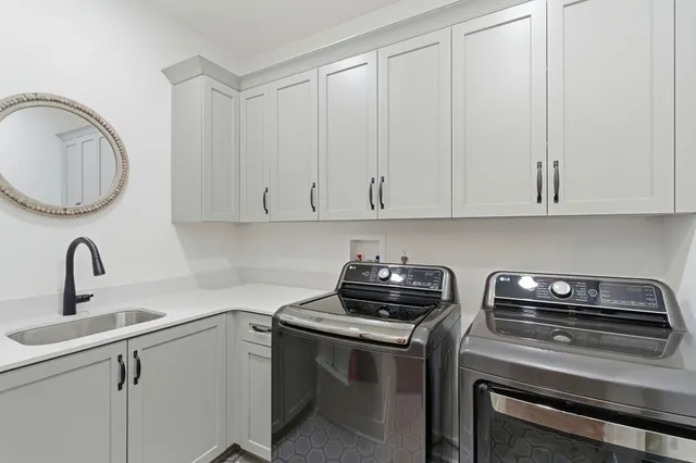 a large white kitchen with a refrigerator a sink dishwasher a stove and white cabinets with wooden floor