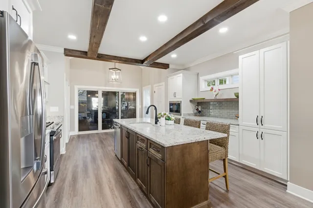 a kitchen with granite countertop a stove top oven a sink dishwasher a refrigerator and wooden floor