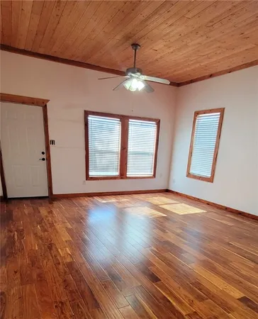 a view of an empty room with wooden floor and fan