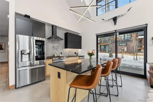 a kitchen with stainless steel appliances granite countertop a stove a refrigerator a kitchen island with chairs and refrigerator