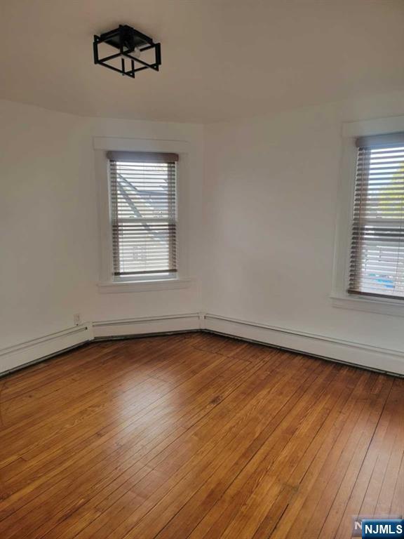 139 Union Place, Unit 2 Ridgefield Park, NJ 07660 - Photo 3 of 14 an empty room with wooden floor chandelier fan and windows