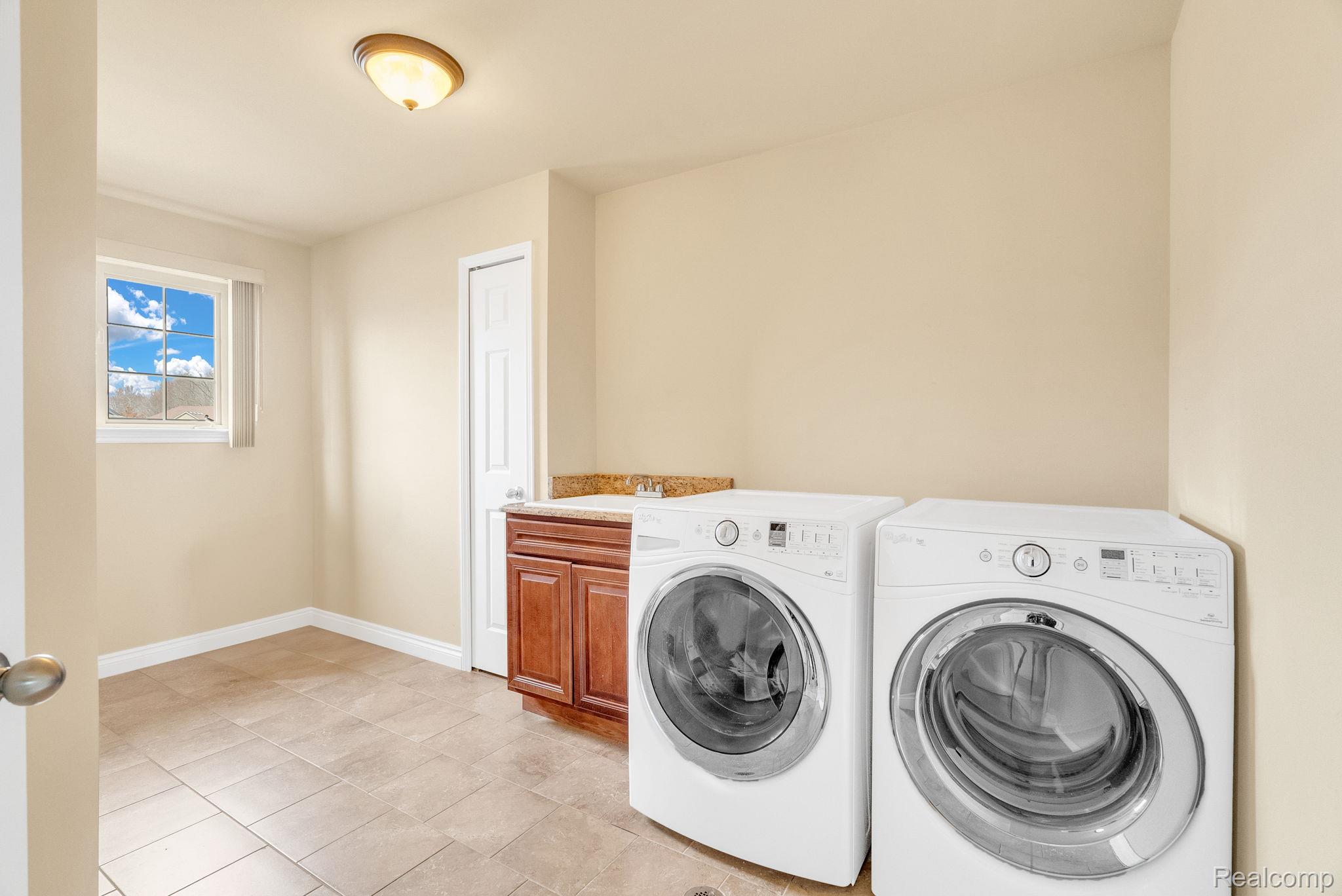 4122 Hawks Nest Road Utica, MI 48317 - Photo 54 of 74 Laundry area featuring washer and clothes dryer, light tile patterned floors, and cabinet space