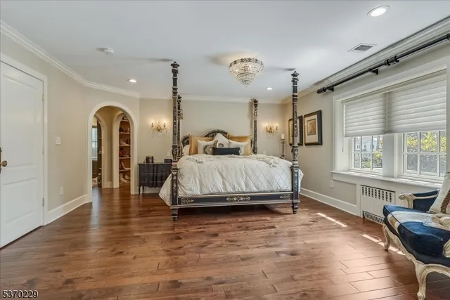 a spacious bedroom with a large bed a chandelier and windows
