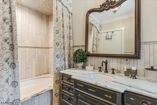 a bathroom with a granite countertop sink a mirror a vanity and a bathtub