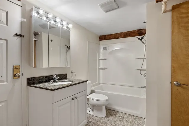 a bathroom with a granite countertop sink toilet and shower