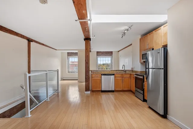 a kitchen with sink a refrigerator and wooden floor