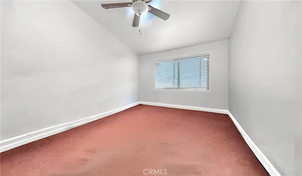 an empty room with a chandelier fan and windows