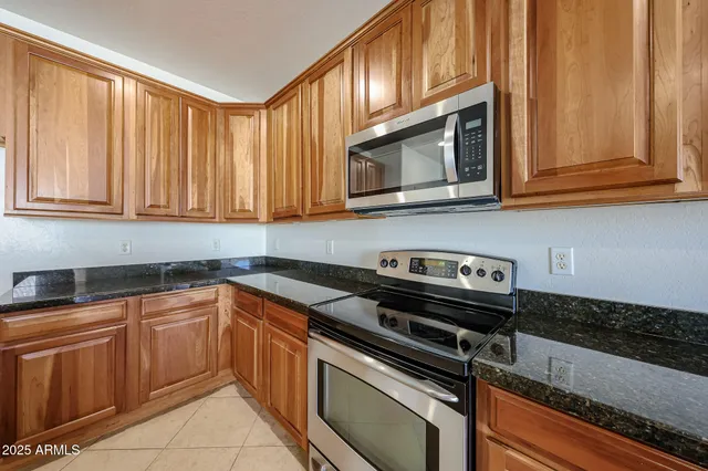 a kitchen with granite countertop a stove top oven microwave oven cabinets and a counter space