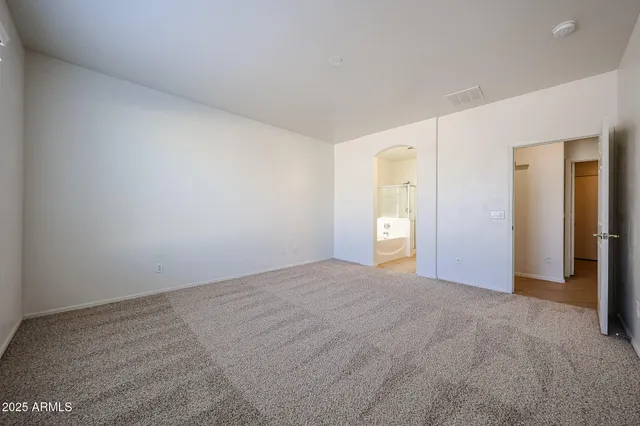 a view of an empty room with window and bathroom