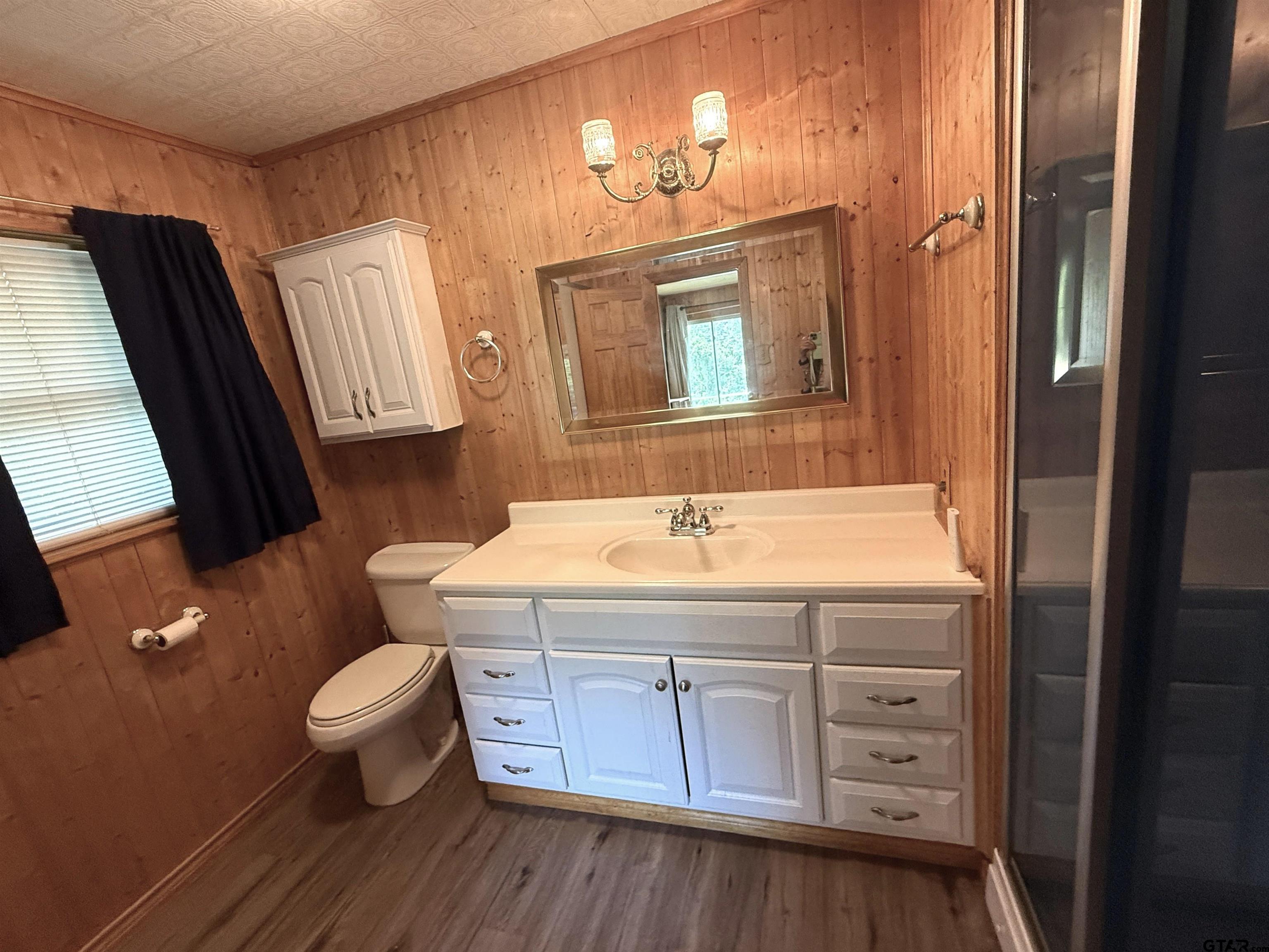 2015 East 5th Street Tyler, TX 75701 - Photo 14 of 32 a bathroom with a granite countertop toilet a sink and a mirror