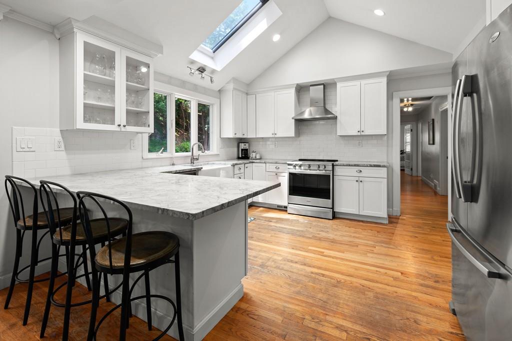 20 Cliff Road Wellesley, MA 02481 - Photo 5 of 21 a kitchen with stainless steel appliances granite countertop a stove a sink dishwasher a refrigerator with a dining table and chairs