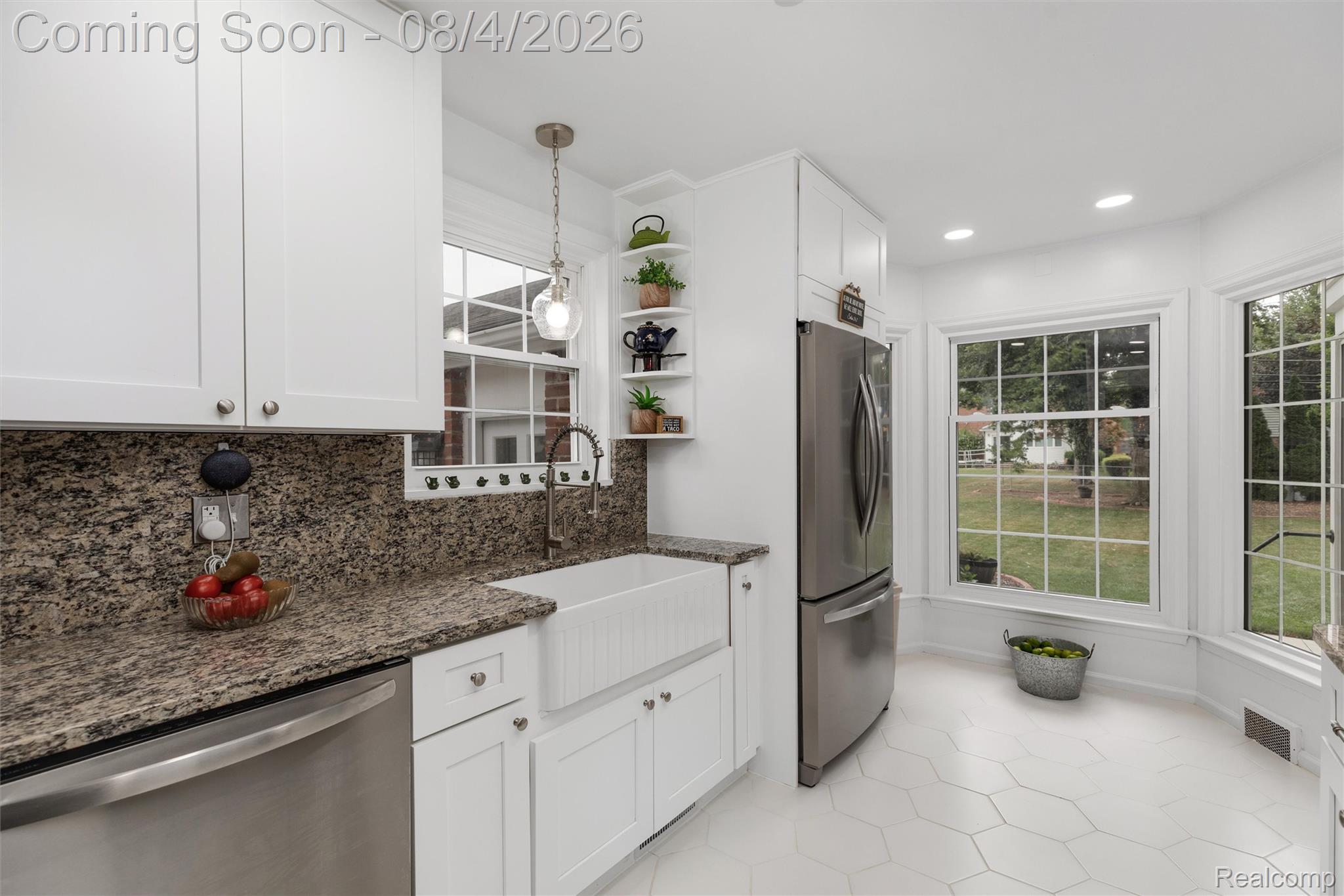 1729 Broadstone Road Grosse Pointe, MI 48236 - Photo 10 of 39 Kitchen featuring white cabinetry, stone countertops, a farmhouse-style sink, stainless steel appliances, and a bay window