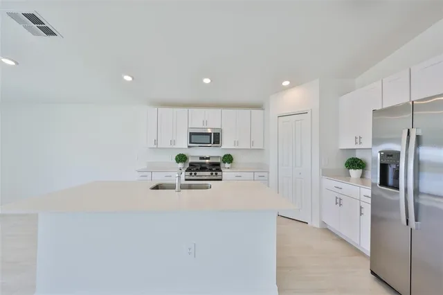 a view of kitchen with kitchen island white cabinets and refrigerator