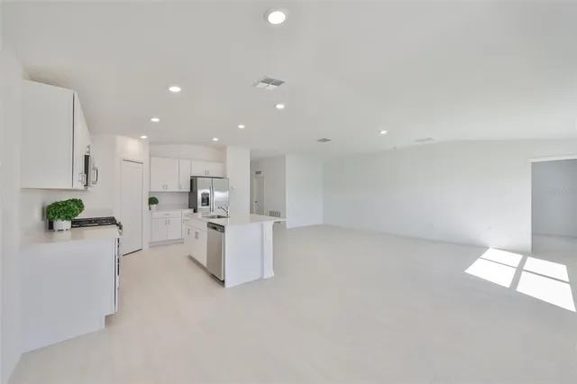 a kitchen that has a lot of white cabinets and stainless steel appliances