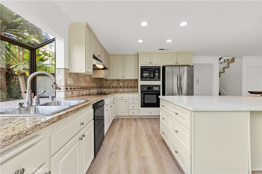 19 Alameda Irvine, CA 92620 - Photo 26 of 55 a large kitchen with stainless steel appliances kitchen island granite countertop a refrigerator a sink dishwasher a stove with wooden cabinets and floors