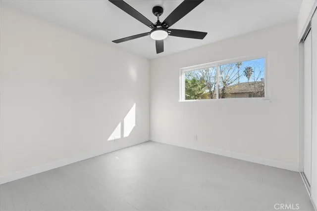 an empty room with windows and fan