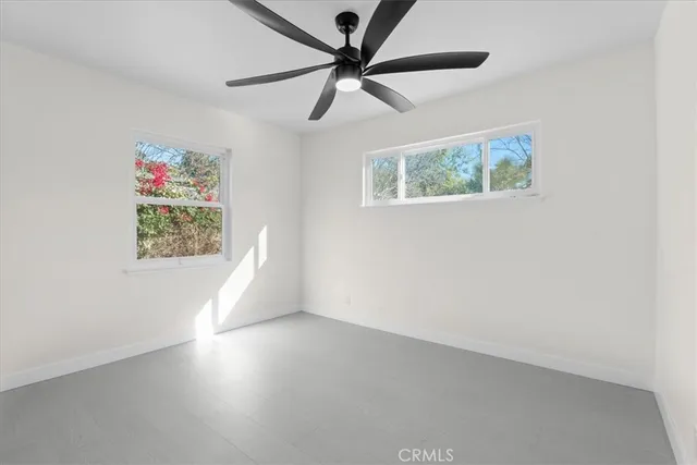 an empty room with windows and fan