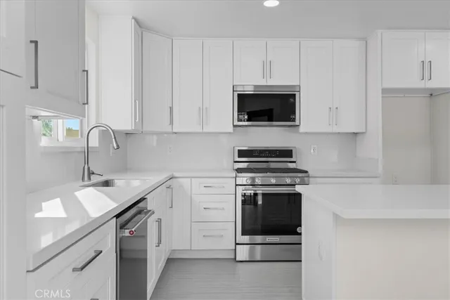 a kitchen with white cabinets and stainless steel appliances