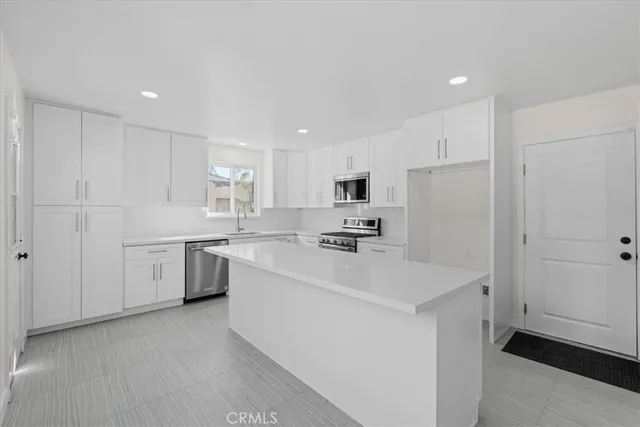 a kitchen with a sink a stove a refrigerator and white cabinets