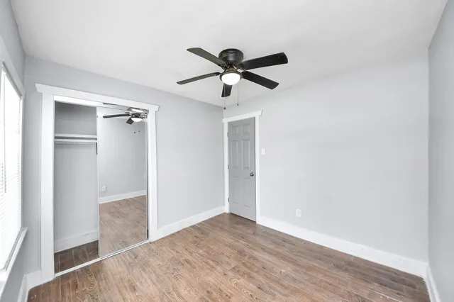 a view of empty room with wooden floor and ceiling fan