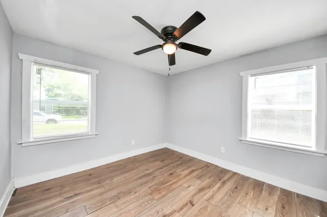 a view of an empty room with wooden floor and a window