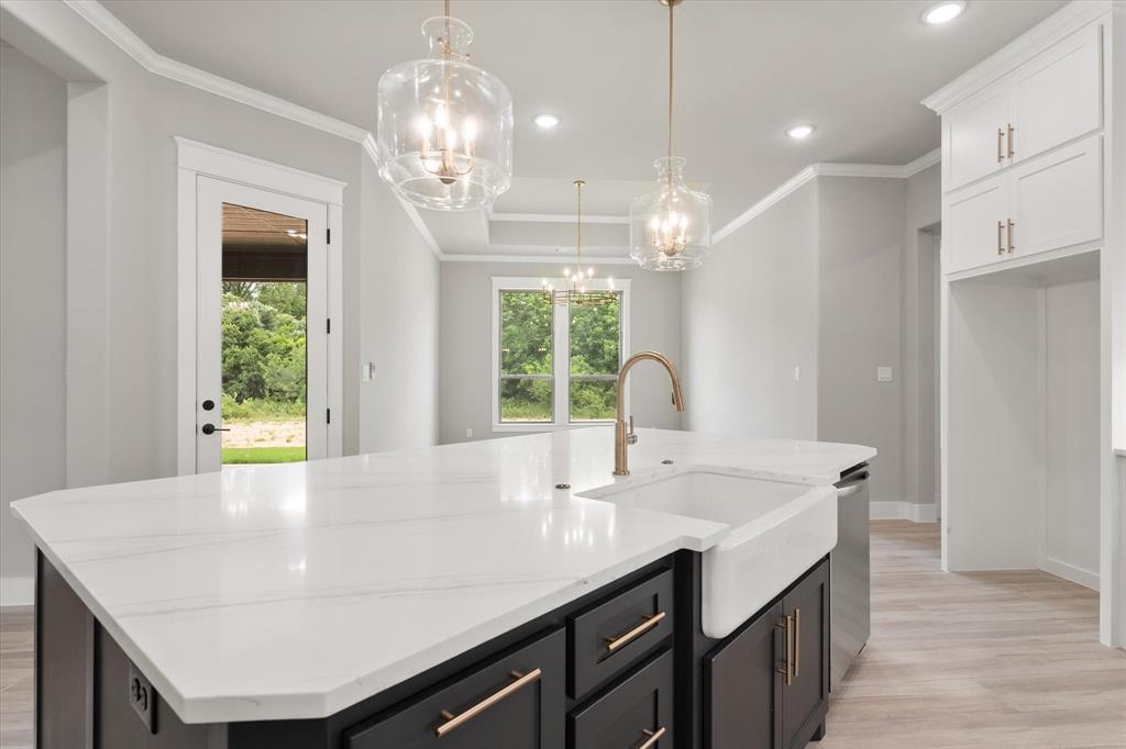 6610 Waggoner Way Midlothian, TX 76065 - Photo 11 of 40 Kitchen island featuring a white apron-front sink, a gold-finish faucet, and a light-toned countertop