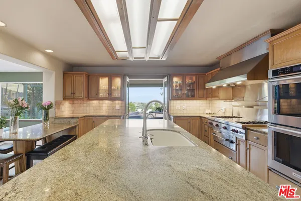 a large kitchen with stainless steel appliances a large counter top a stove and a sink