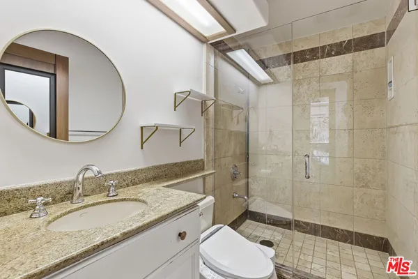 a bathroom with a granite countertop sink toilet a mirror and shower
