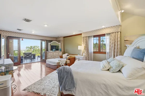 a bedroom with a large bed and large windows