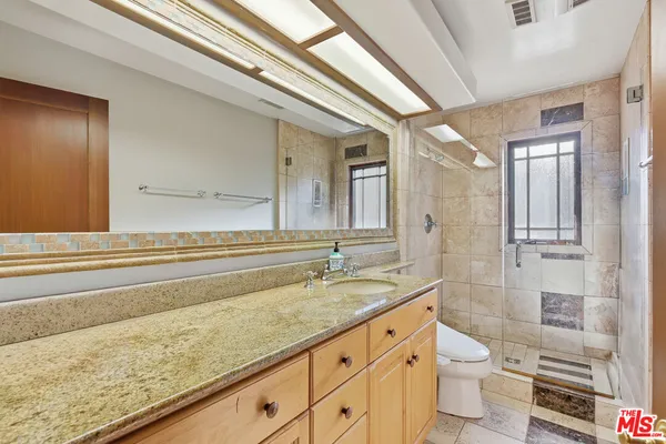 a bathroom with a granite countertop sink toilet and shower