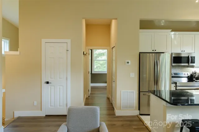 a view of a kitchen with refrigerator and wooden floor
