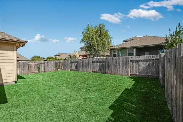 a view of a backyard with plants and wooden fence