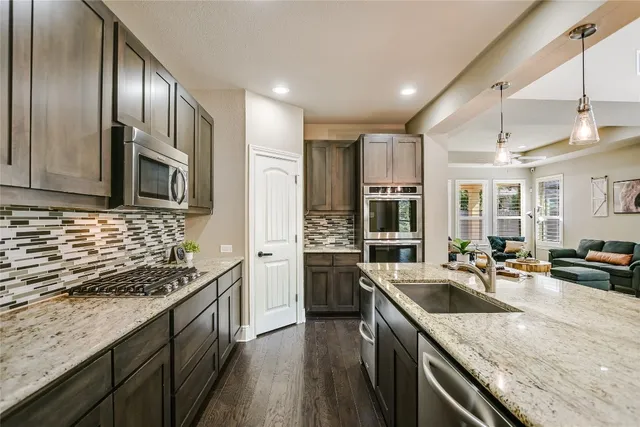 a kitchen with stainless steel appliances granite countertop a sink stove and refrigerator
