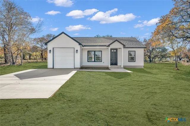 a front view of a house with a garden and trees