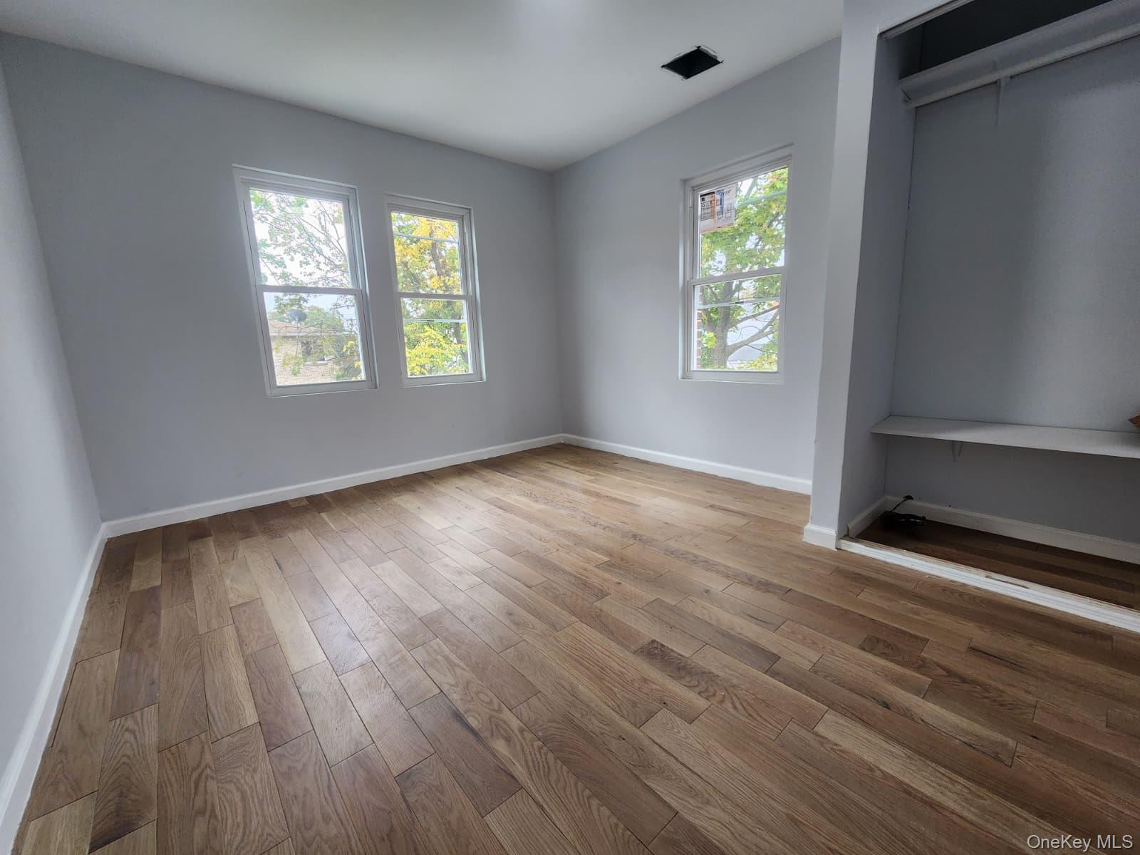 221-26 134th Road Queens, NY 11413 - Photo 20 of 30 an empty room with wooden floor and windows