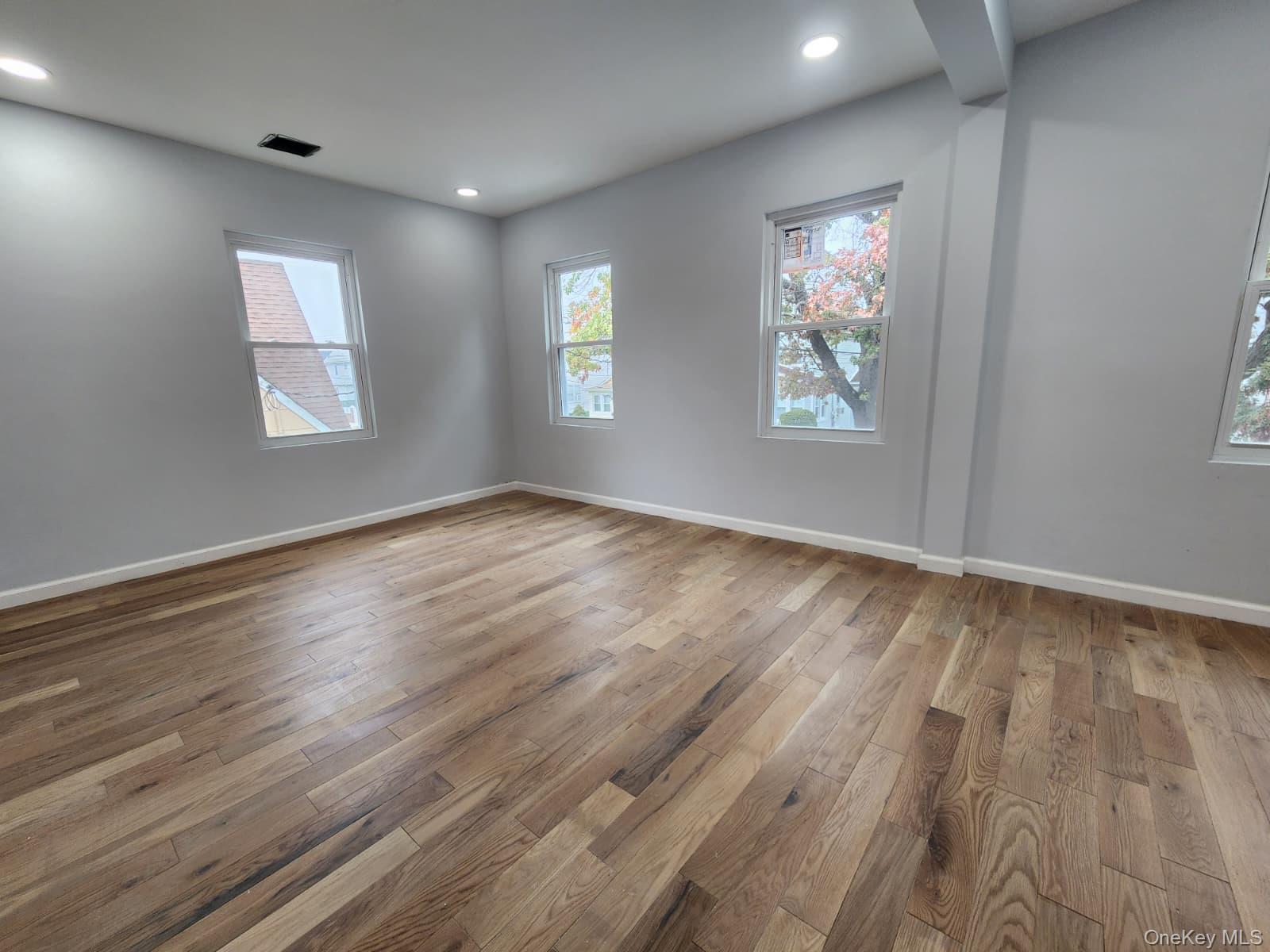 221-26 134th Road Queens, NY 11413 - Photo 21 of 30 an empty room with wooden floor and windows