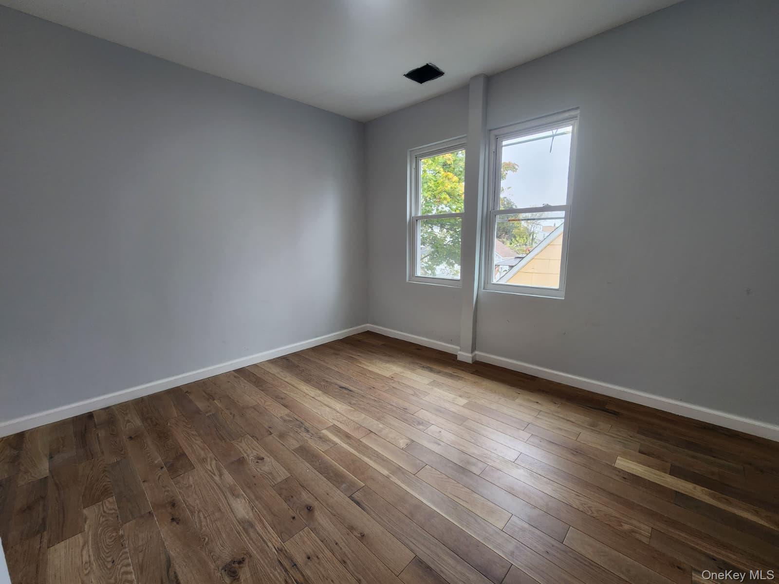 221-26 134th Road Queens, NY 11413 - Photo 24 of 30 an empty room with wooden floor and windows