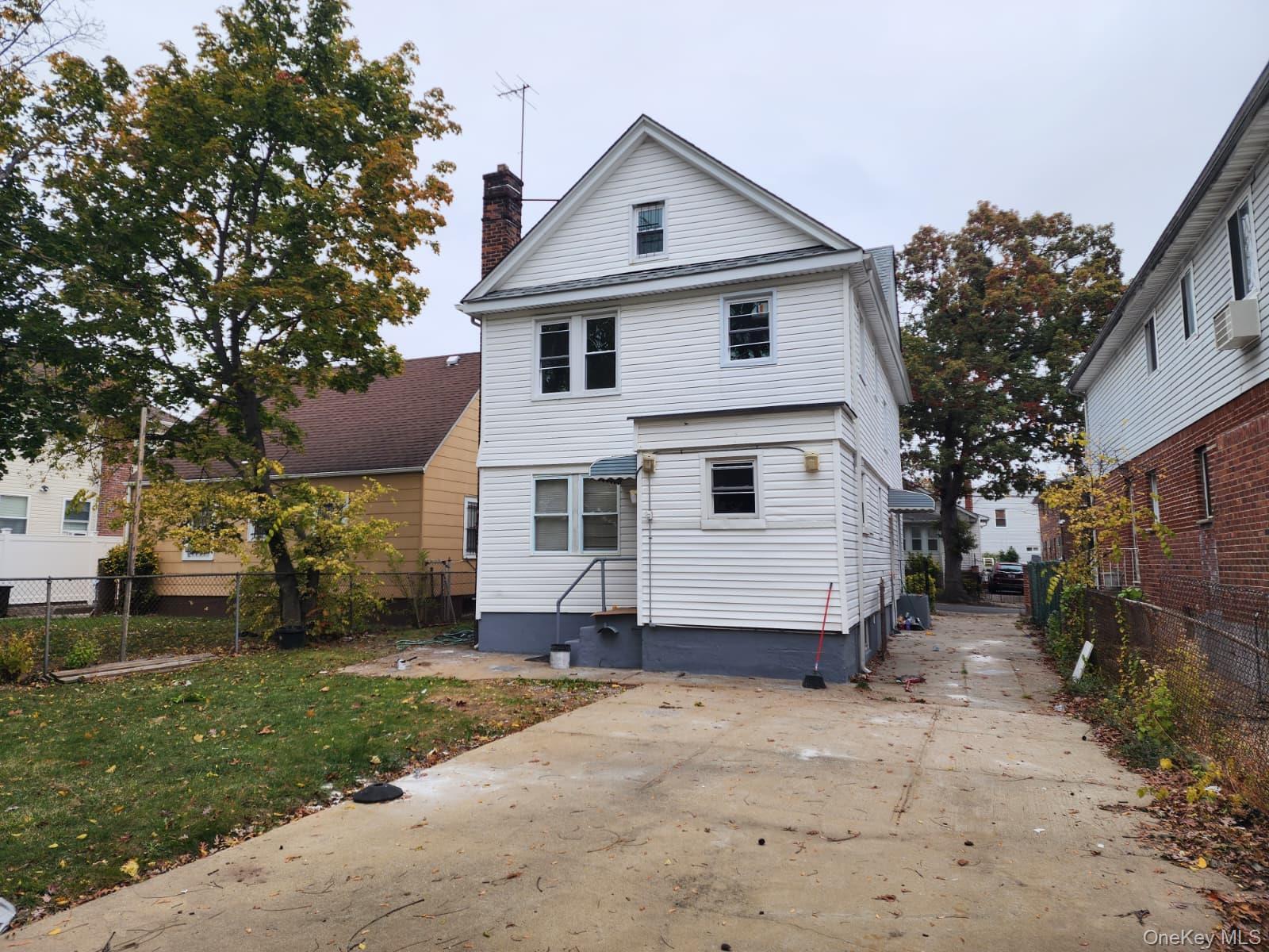 221-26 134th Road Queens, NY 11413 - Photo 27 of 30 a white house covered with tall trees