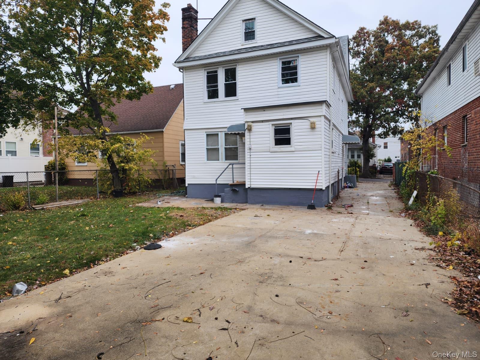 221-26 134th Road Queens, NY 11413 - Photo 28 of 30 a view of a white house next to a yard and a large tree