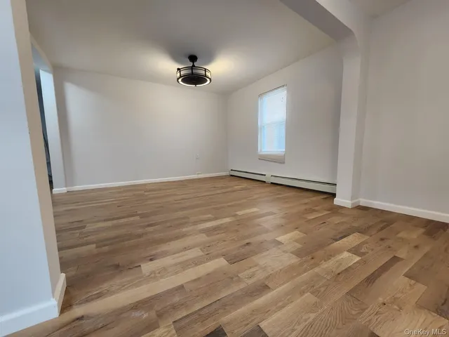 an empty room with wooden floor chandelier fan and windows